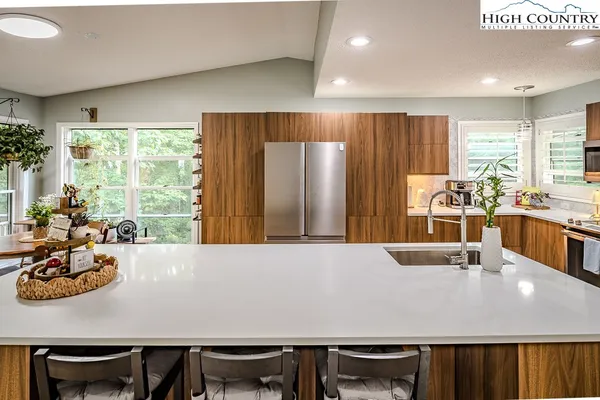 a view of kitchen island with stainless steel appliances furniture large window and wooden floor