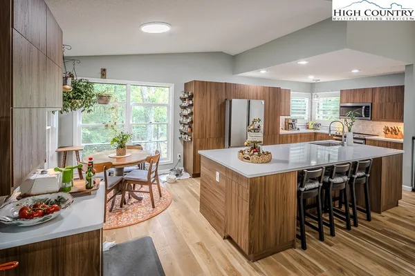 a kitchen with stainless steel appliances granite countertop a stove a refrigerator a kitchen island a table and chairs in it