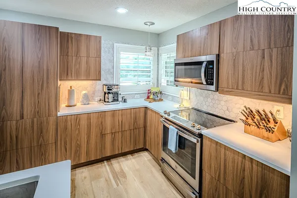 a kitchen with stainless steel appliances granite countertop a stove a sink dishwasher and a microwave oven with white cabinets