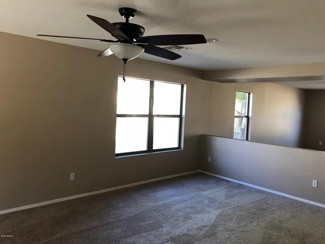 an empty room with a window and a fan