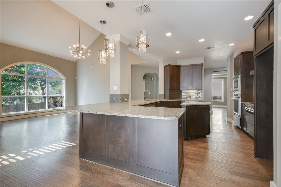 3513 Grimes Ranch Road Austin, TX 78732 - Photo 8 of 32 Kitchen with a chandelier, a peninsula, vaulted ceiling, decorative backsplash, and a sink