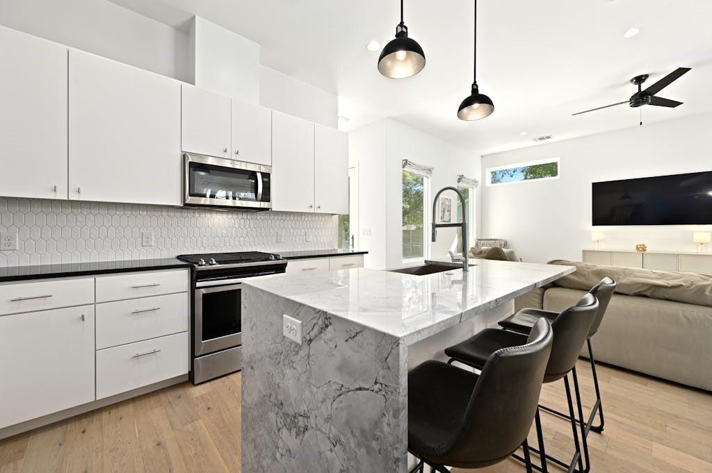 5212 Huisache Street, Unit 2 Austin, TX 78751 - Photo 30 of 30 Kitchen with a breakfast bar, stainless steel appliances, open floor plan, white cabinets, and light wood-style flooring