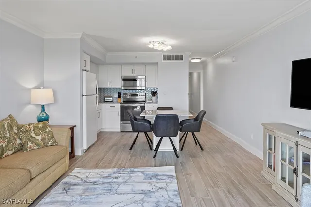 a living room with stainless steel appliances furniture a flat screen tv and a couch