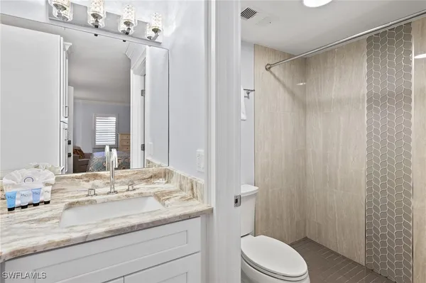 a bathroom with a granite countertop sink toilet and shower