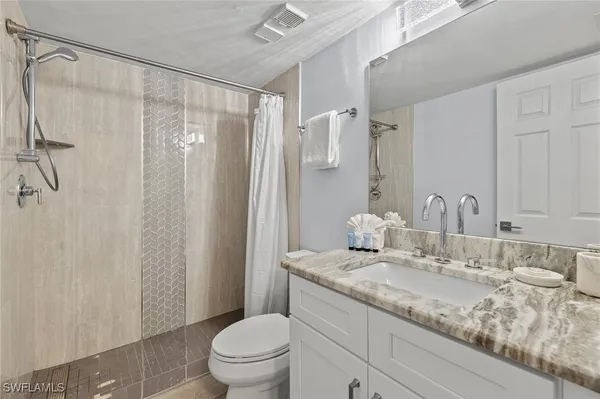 a bathroom with a granite countertop sink a toilet and shower