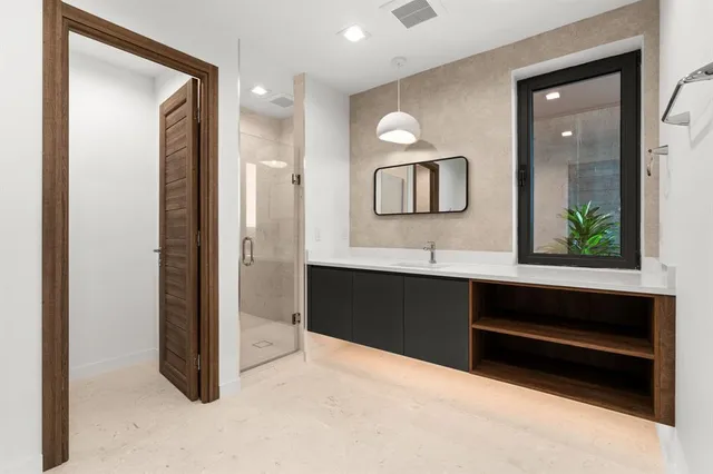 a spacious bathroom with a double vanity sink a large mirror and shower