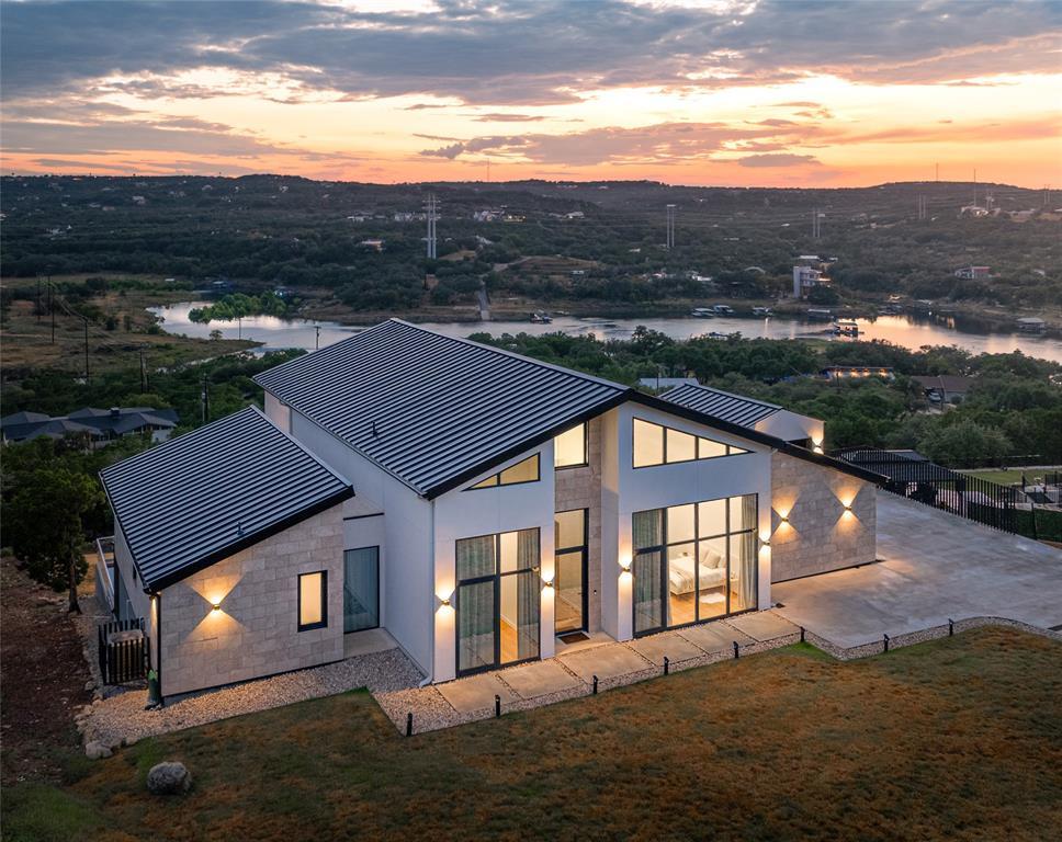 2714 Lakehurst Road Spicewood, TX 78669 - Photo 37 of 37 Back of property at dusk with a patio, a standing seam roof, a metal roof, stucco siding, and stone siding