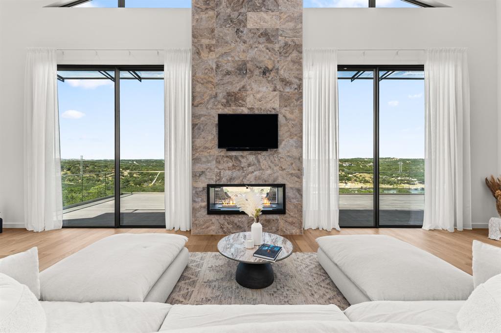 2714 Lakehurst Road Spicewood, TX 78669 - Photo 6 of 37 Living room with a multi sided fireplace, plenty of natural light, and light wood-style floors