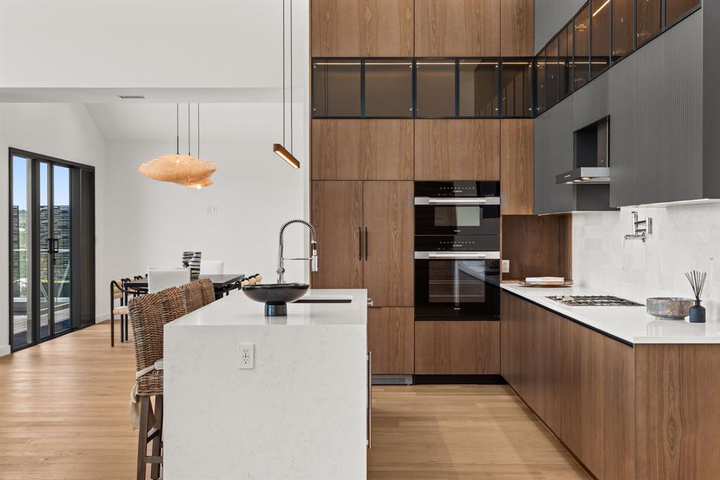 2714 Lakehurst Road Spicewood, TX 78669 - Photo 8 of 37 Kitchen featuring light stone counters, a breakfast bar, modern cabinets, pendant lighting, and light wood-style flooring