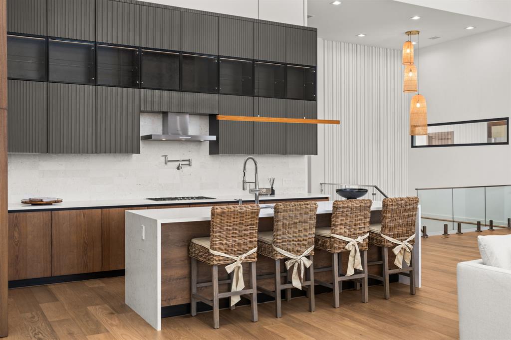 2714 Lakehurst Road Spicewood, TX 78669 - Photo 10 of 37 Kitchen with a kitchen breakfast bar, hanging light fixtures, light stone countertops, modern cabinets, and an island with sink