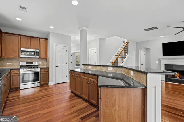 a large kitchen with stainless steel appliances granite countertop a stove sink refrigerator and cabinets