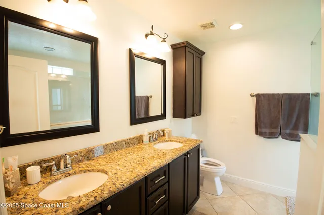 a bathroom with a granite countertop sink double vanity and mirror