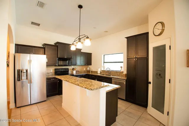 a kitchen with stainless steel appliances granite countertop a refrigerator a stove a sink and a refrigerator