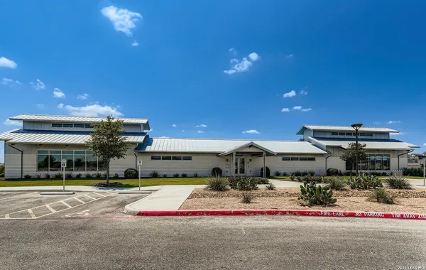 a front view of a building with streets and trees