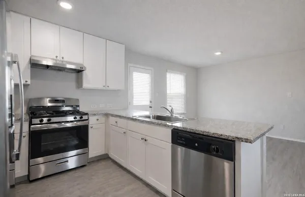 a kitchen with granite countertop white cabinets stainless steel appliances and a sink