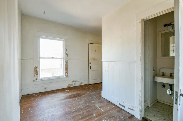 an empty room with wooden floor cabinet and windows