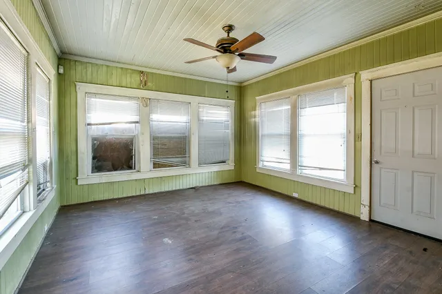 a view of an empty room with a window and wooden floor