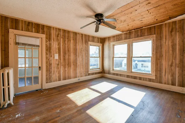 a view of an empty room with a window and wooden floor