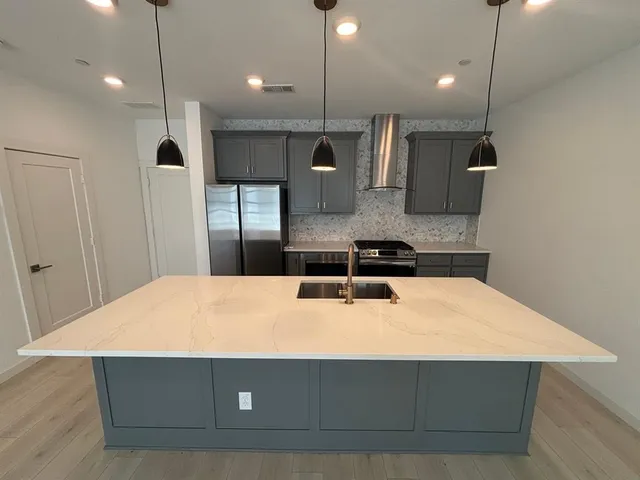 a kitchen with kitchen island a stove a sink a refrigerator and chairs