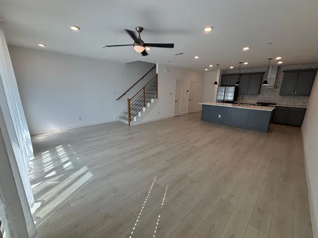 a kitchen with a sink a stove a refrigerator and white cabinets with wooden floor