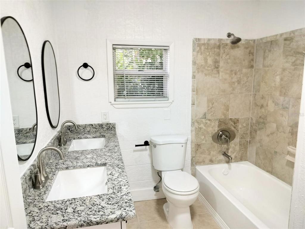 9901 Grace Drive Port Richey, FL 34668 - Photo 15 of 35 a bathroom with a granite countertop toilet sink and shower