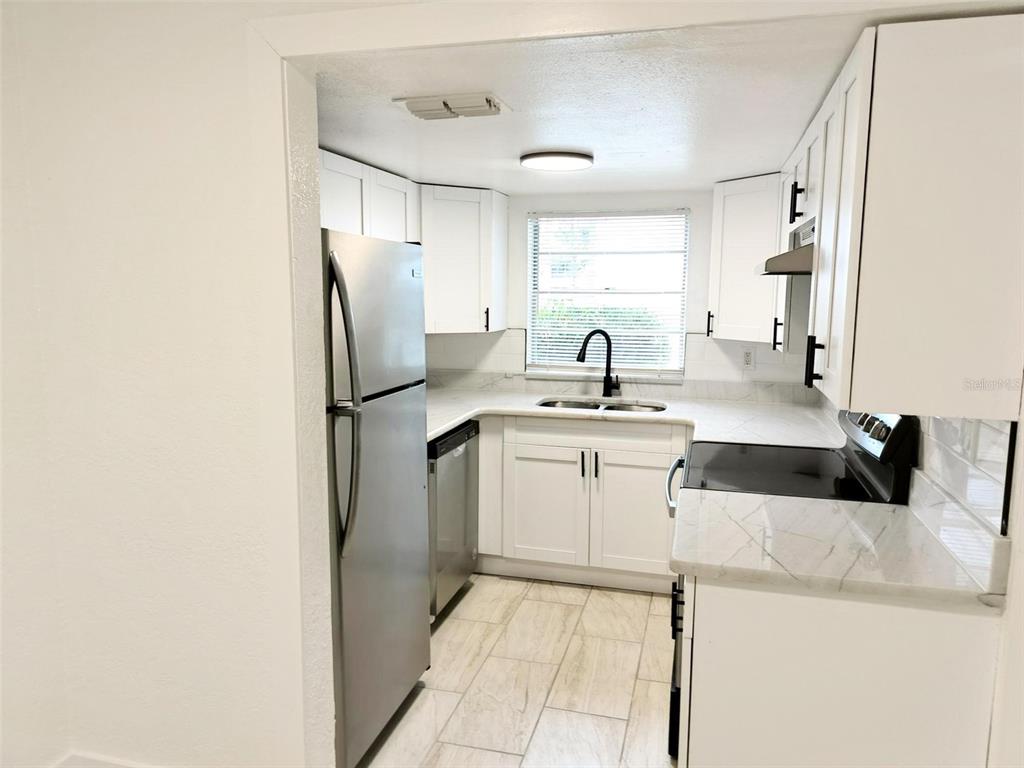 9901 Grace Drive Port Richey, FL 34668 - Photo 23 of 35 a kitchen with a sink cabinets and refrigerator