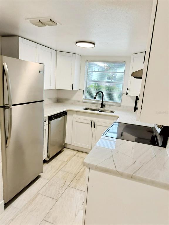 9901 Grace Drive Port Richey, FL 34668 - Photo 24 of 35 a kitchen with a sink a refrigerator and white cabinets
