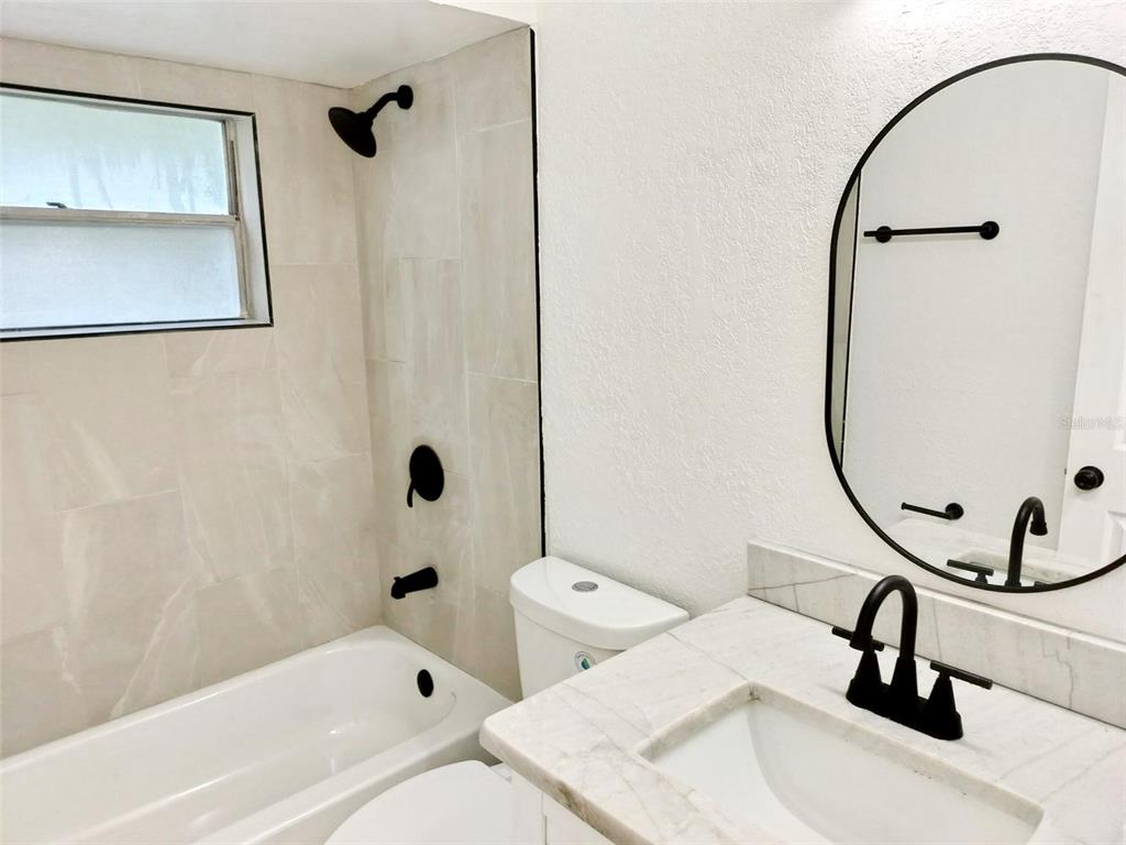 9901 Grace Drive Port Richey, FL 34668 - Photo 31 of 35 a bathroom with a sink a toilet and a mirror