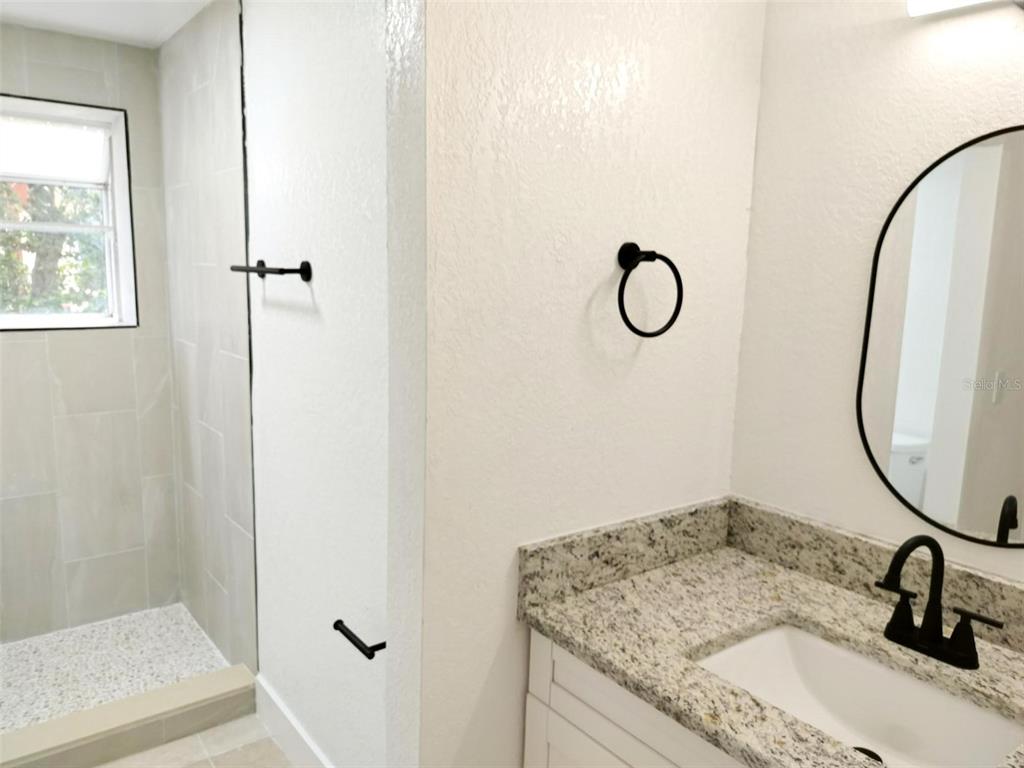 9901 Grace Drive Port Richey, FL 34668 - Photo 6 of 35 a bathroom with a granite countertop sink a toilet and a mirror