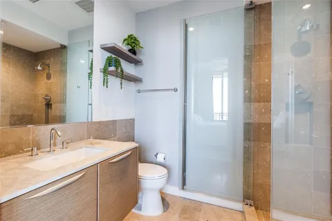 a bathroom with a granite countertop sink a toilet and shower