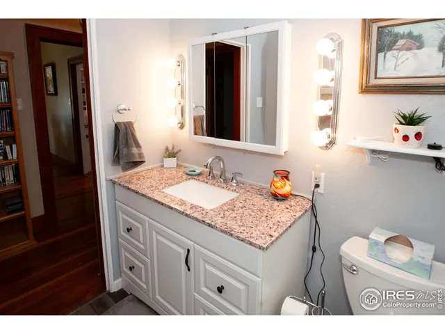 a bathroom with a granite countertop sink a toilet and a mirror