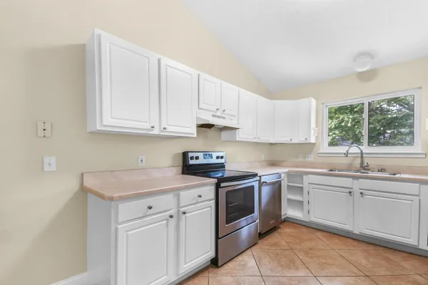 a kitchen with white cabinets sink and appliances