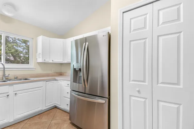 a kitchen with stainless steel appliances granite countertop a refrigerator and white cabinets