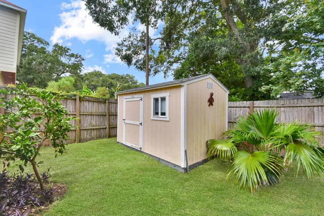 a backyard of a white house with potted plants and large tree