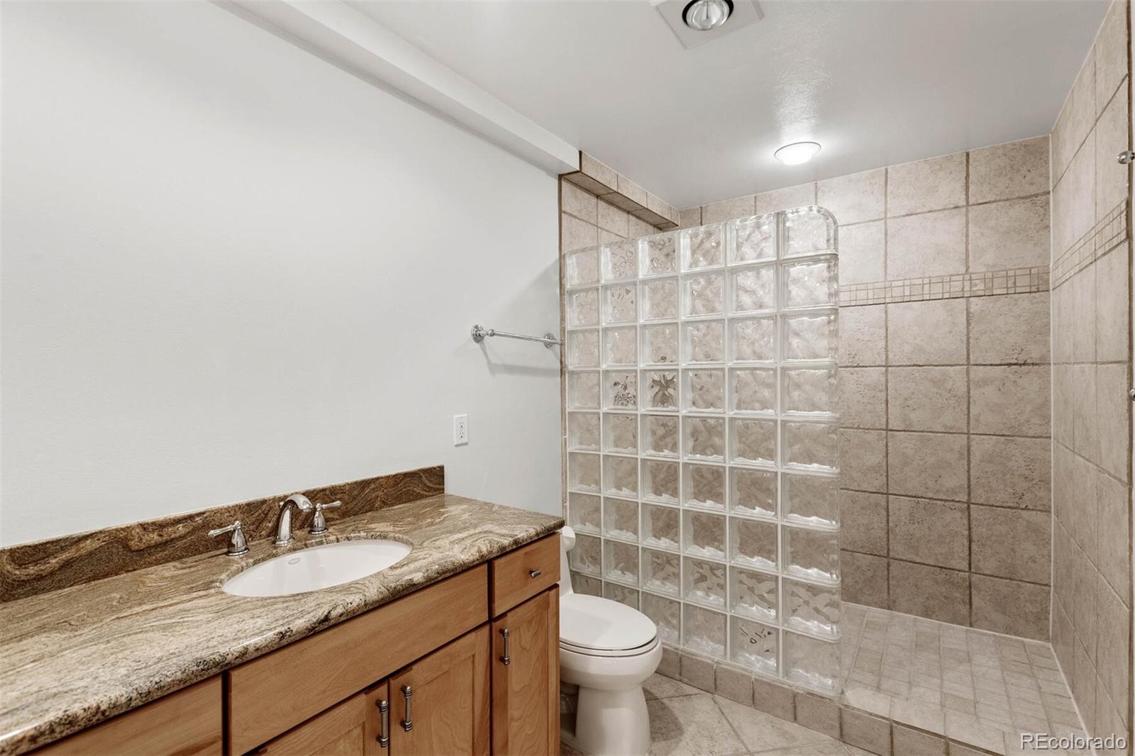 470 Monroe Street Denver, CO 80206 - Photo 38 of 40 a bathroom with a granite countertop sink a toilet and a mirror