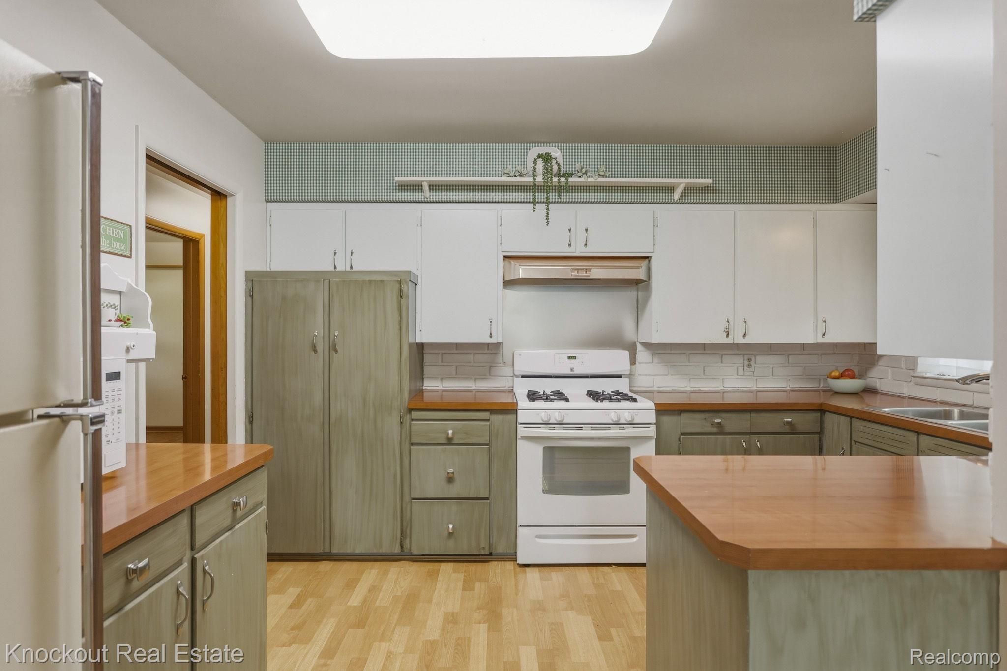 1755 South Reese Road Reese, MI 48757 - Photo 15 of 69 Kitchen featuring wood-finish flooring, wood countertops, a built-in range with hood, and mixed cabinetry with upper white and lower green finishes