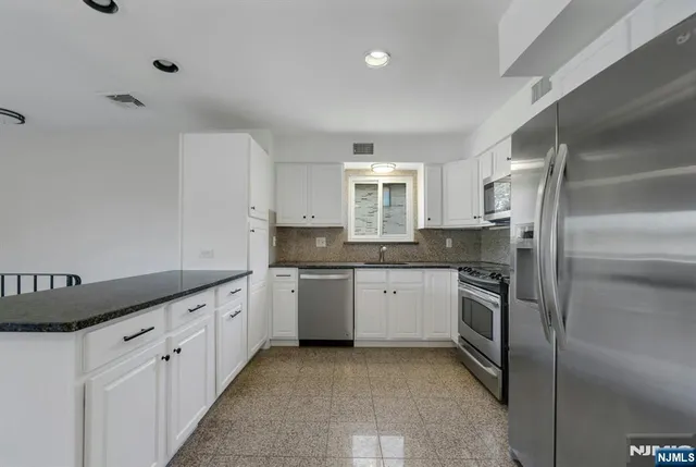 a kitchen with granite countertop cabinets stainless steel appliances and a sink