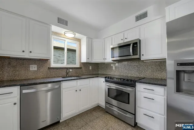 a kitchen with granite countertop white cabinets and white appliances