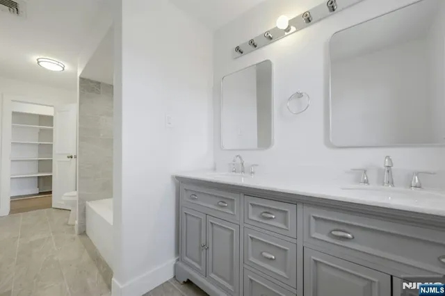 a spacious bathroom with a double vanity sink and mirror