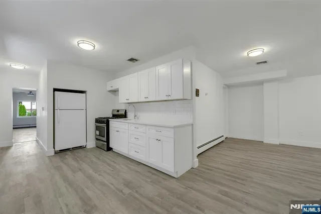 a kitchen with white cabinets and wooden floors