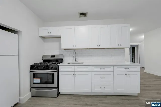 a kitchen with white cabinets and appliances