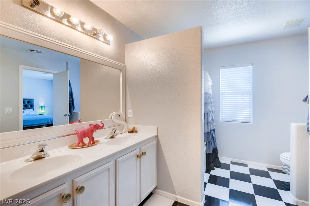 10451 Processor Court Las Vegas, NV 89129 - Photo 18 of 28 A well-lit bathroom with dual sinks and classic checkerboard flooring.