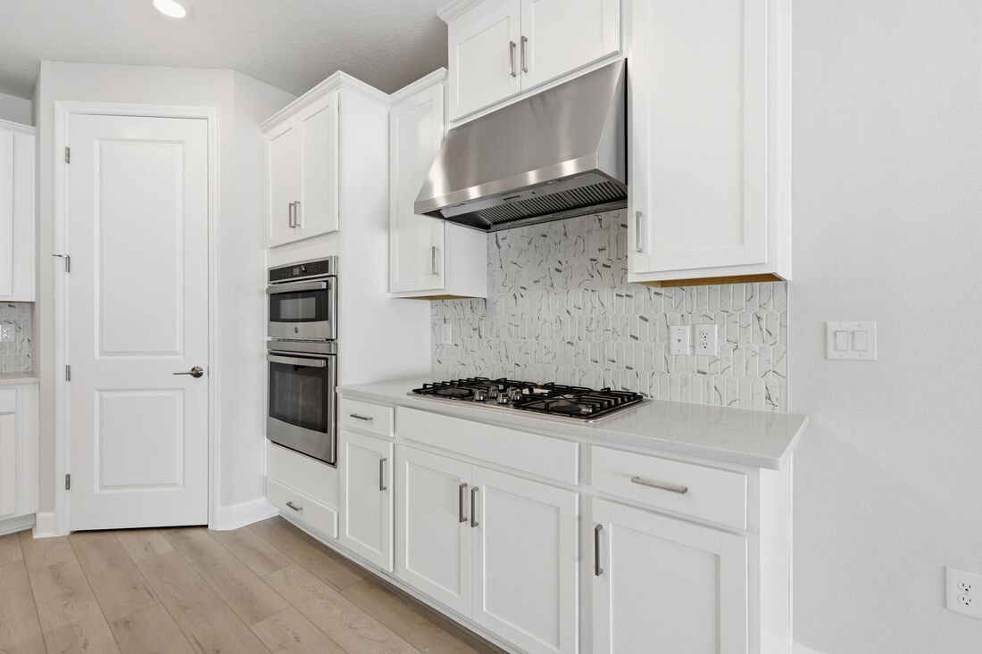 86654 Swift Launch Path Yulee, FL 32097 - Photo 5 of 31 a kitchen with stainless steel appliances a stove a microwave and cabinets