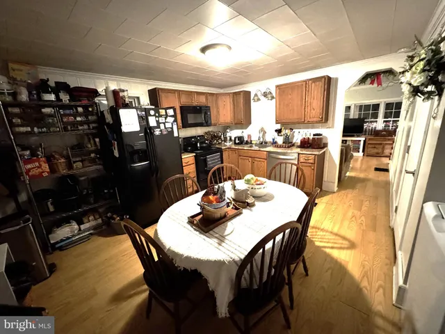 a dining room with stainless steel appliances kitchen island granite countertop a dining table and chairs with wooden floor