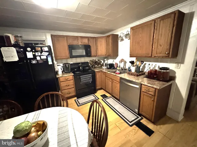 a kitchen with stainless steel appliances a sink a stove top oven a chimney a counter space and cabinets