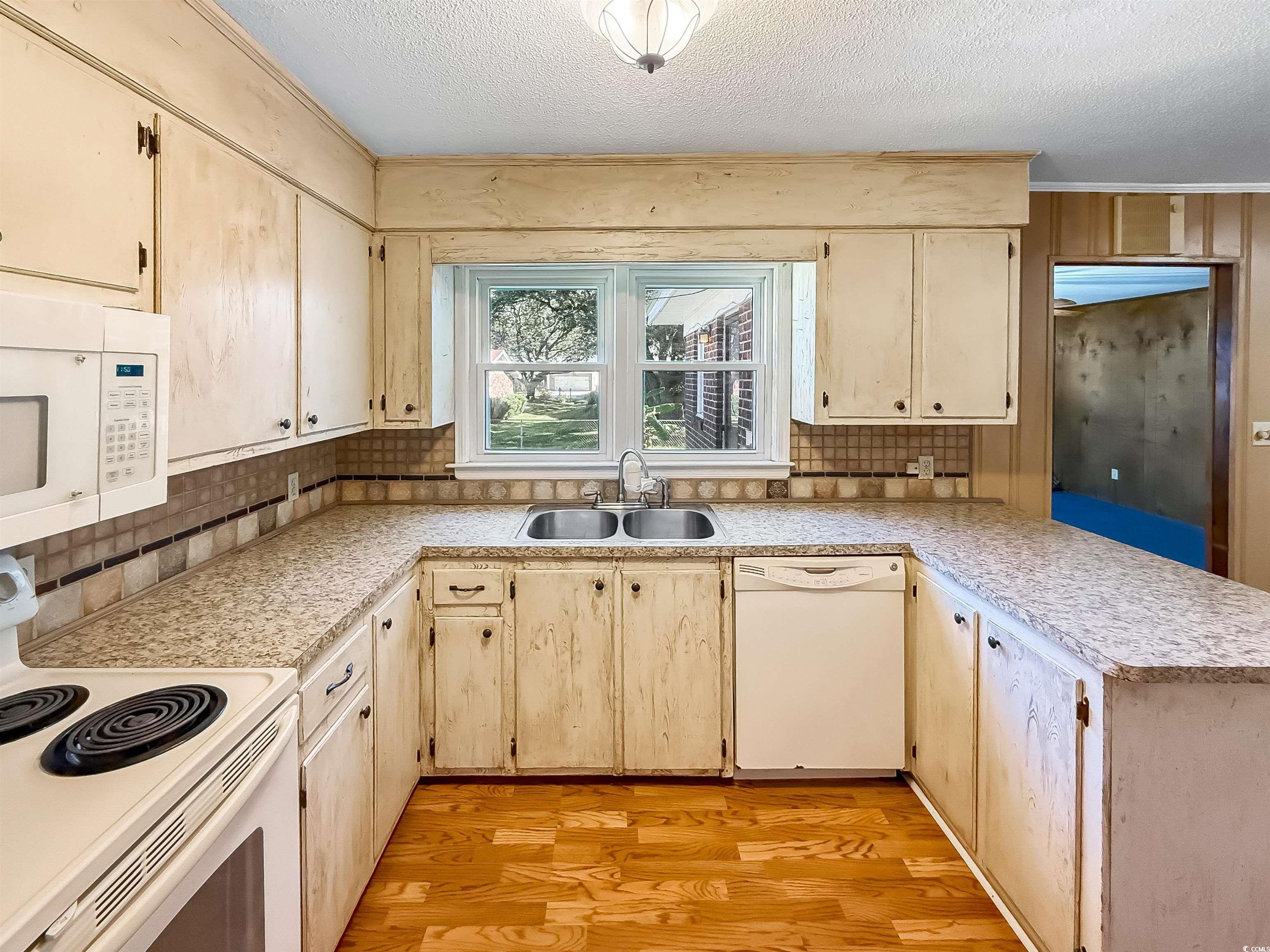 1682 Pickens Street Georgetown, SC 29440 - Photo 15 of 39 Kitchen with white appliances, a peninsula, light countertops, light wood-type flooring, and light brown cabinetry