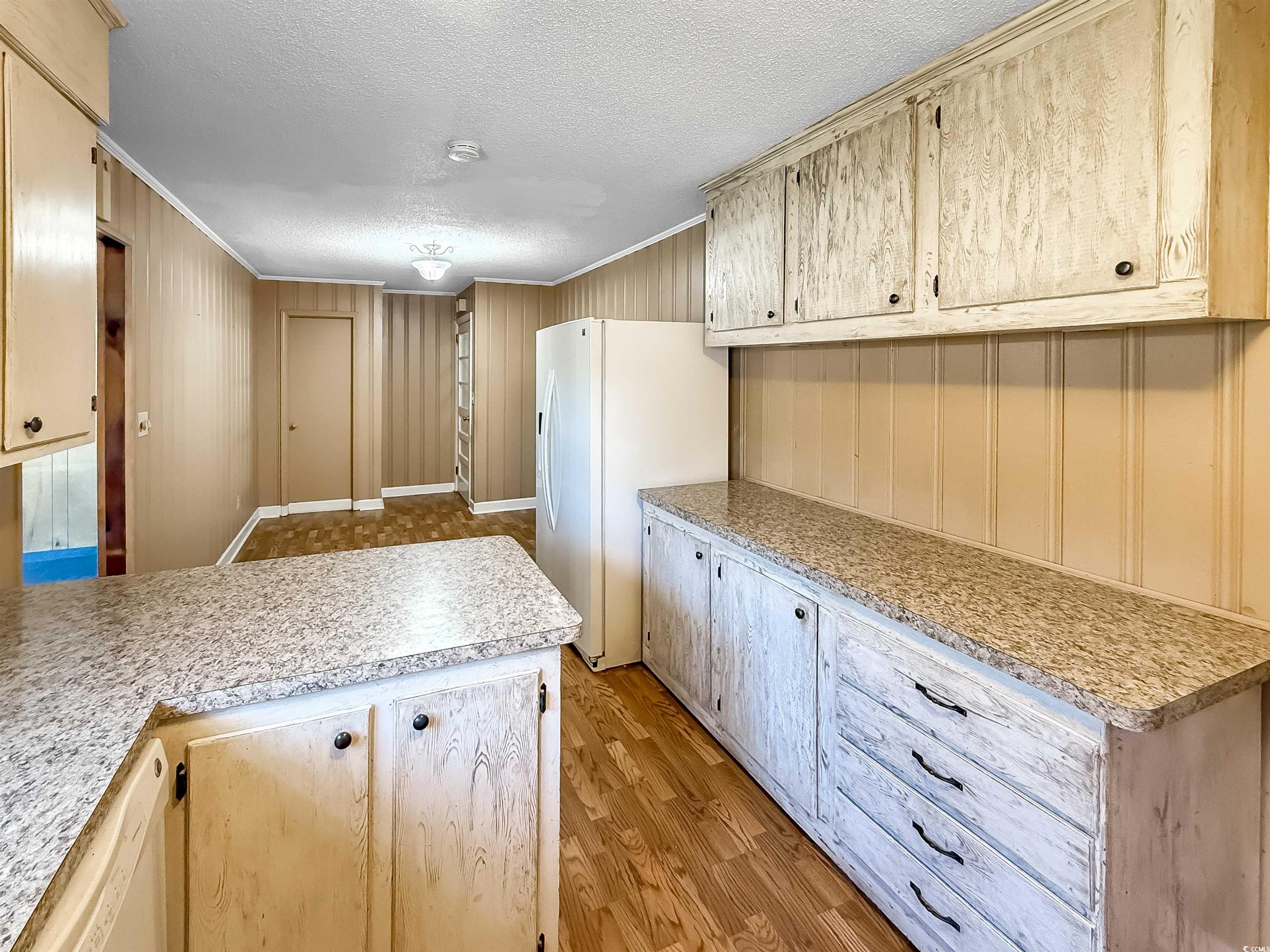 1682 Pickens Street Georgetown, SC 29440 - Photo 19 of 39 Kitchen with ornamental molding, light countertops, white appliances, light wood finished floors, and a textured ceiling