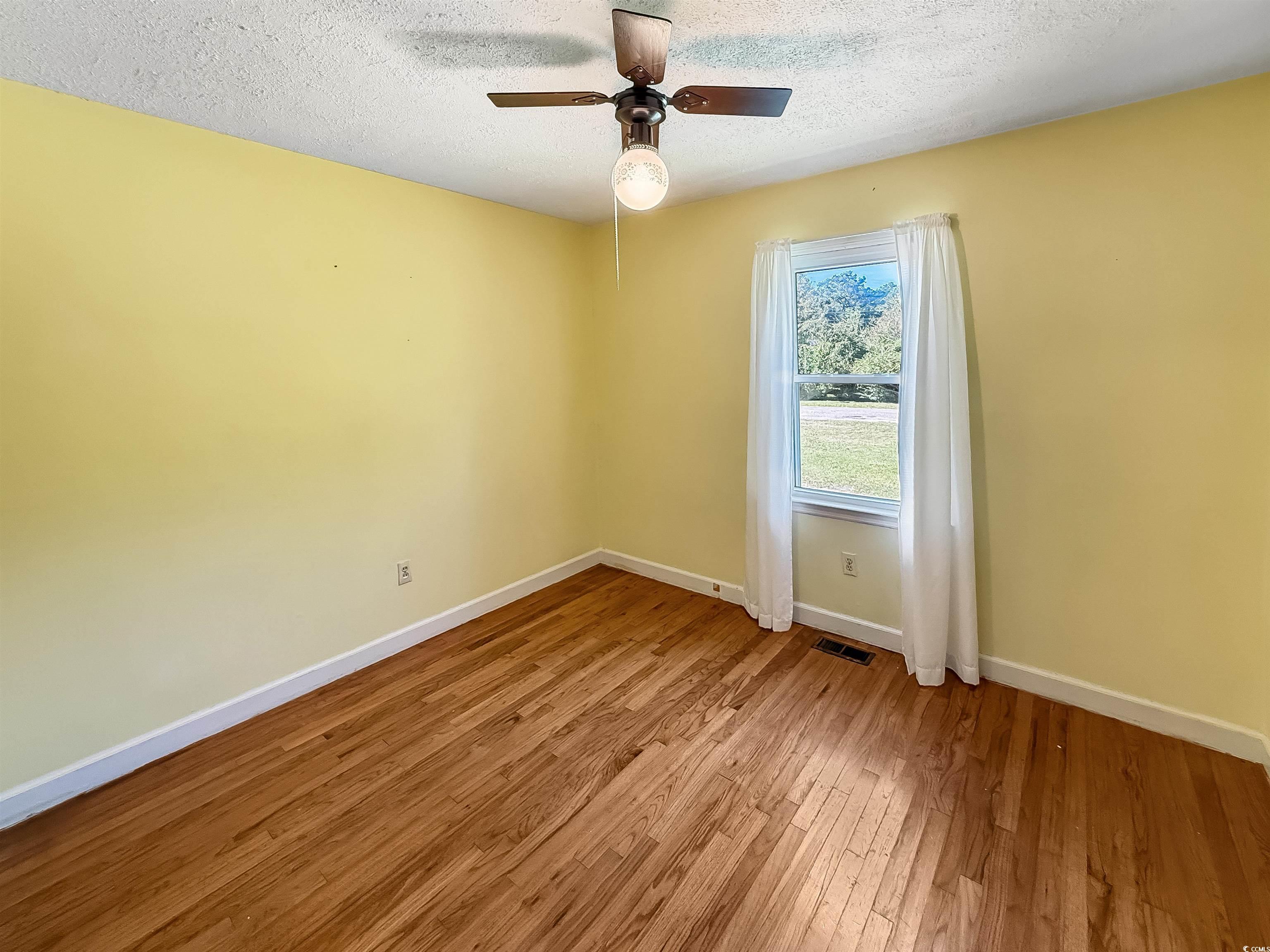 1682 Pickens Street Georgetown, SC 29440 - Photo 22 of 39 Empty room featuring a textured ceiling, light wood-style flooring, and ceiling fan