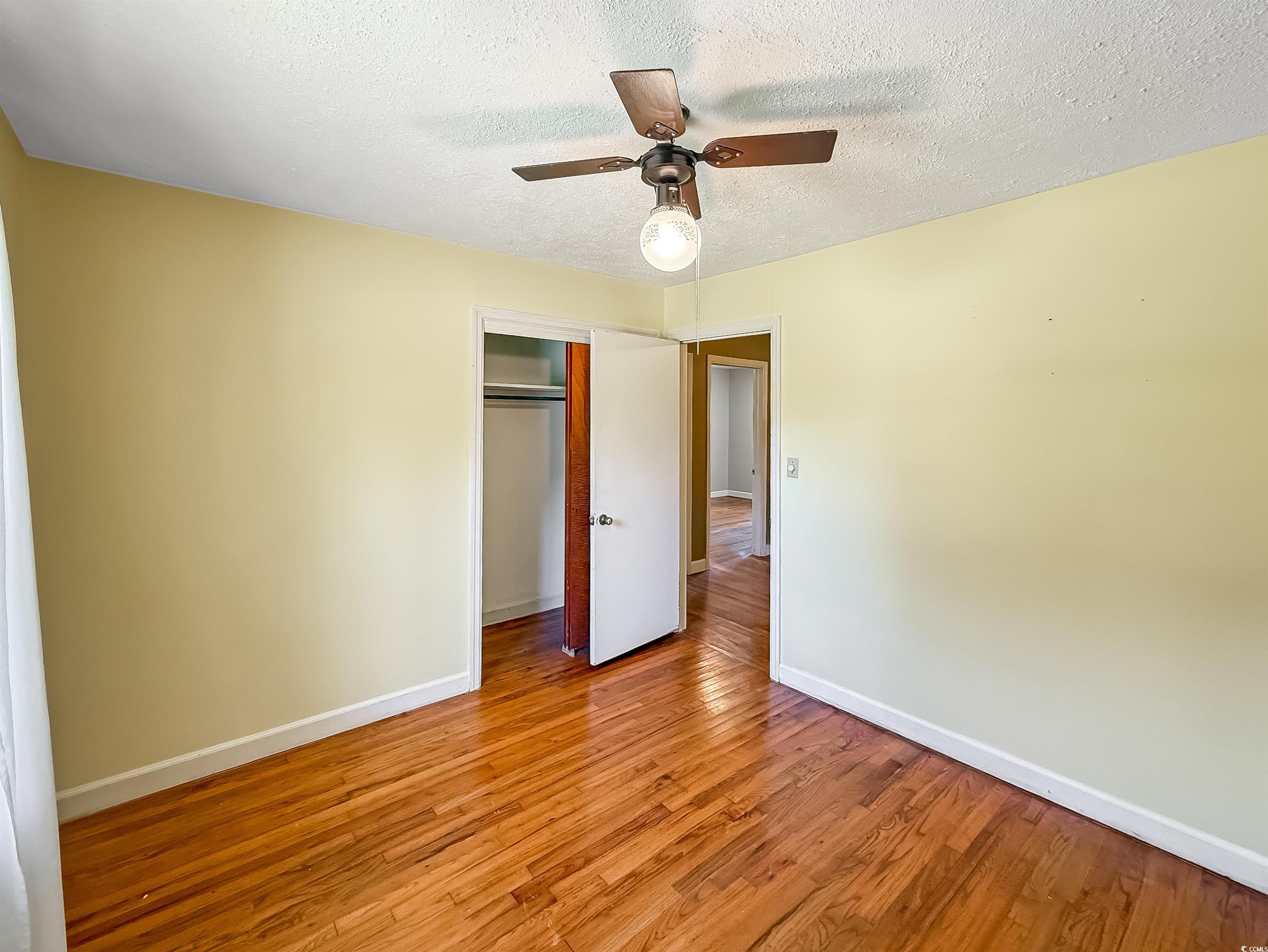 1682 Pickens Street Georgetown, SC 29440 - Photo 23 of 39 Unfurnished bedroom featuring a textured ceiling, light wood-style flooring, a ceiling fan, and a closet