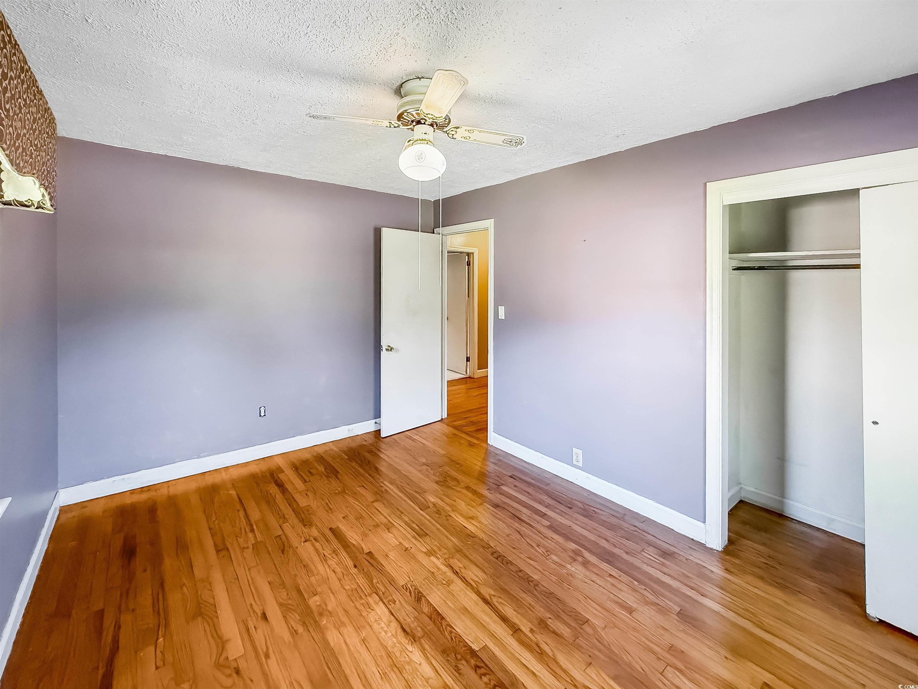1682 Pickens Street Georgetown, SC 29440 - Photo 24 of 39 Unfurnished bedroom featuring a textured ceiling, light wood finished floors, a ceiling fan, and a closet